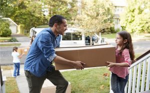 Children Helping Unload Boxes From Van On Family Moving In Day