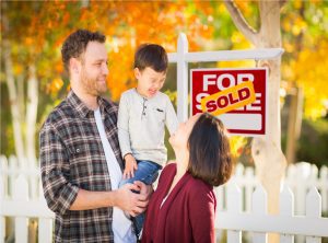 Young Mixed Race Chinese and Caucasian Family In Front of Sold For Sale Real Estate Sign and Fall Yard.