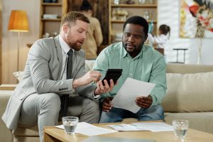 Man uses calculator to advise another man on mortgage interest rates.