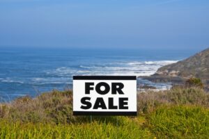 Coastal land with a "LAND FOR SALE" sign