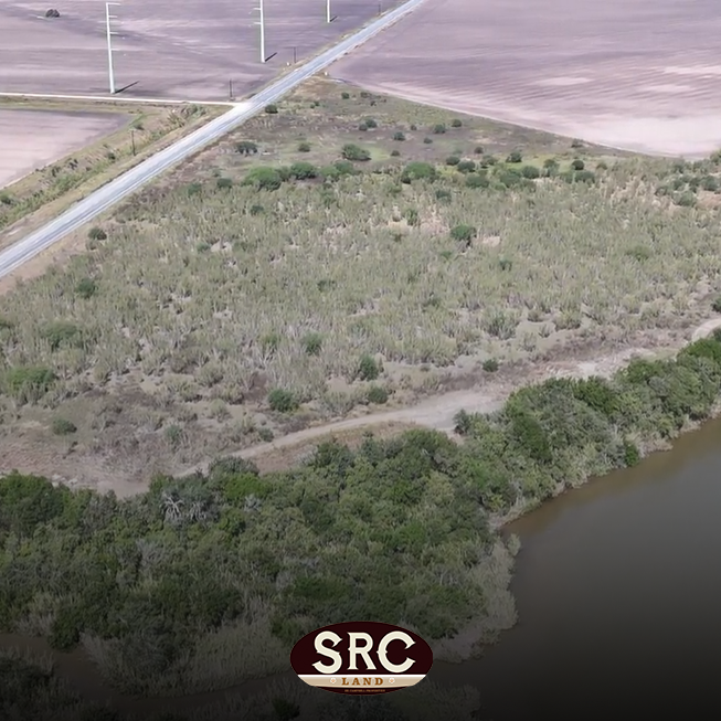 Aerial view of a partly vegetated plot beside a river, with a diagonal road and utility poles crossing the scene; SRC Land watermark at the bottom.